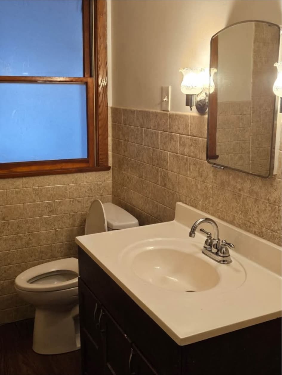 Front-house full bathroom with tiled walls and a vanity