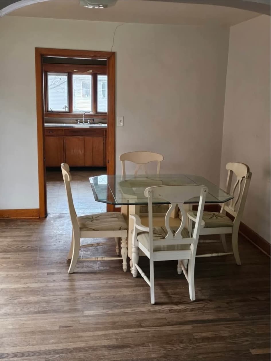 Front-house dining room with hardwood floors, looking into the kitchen