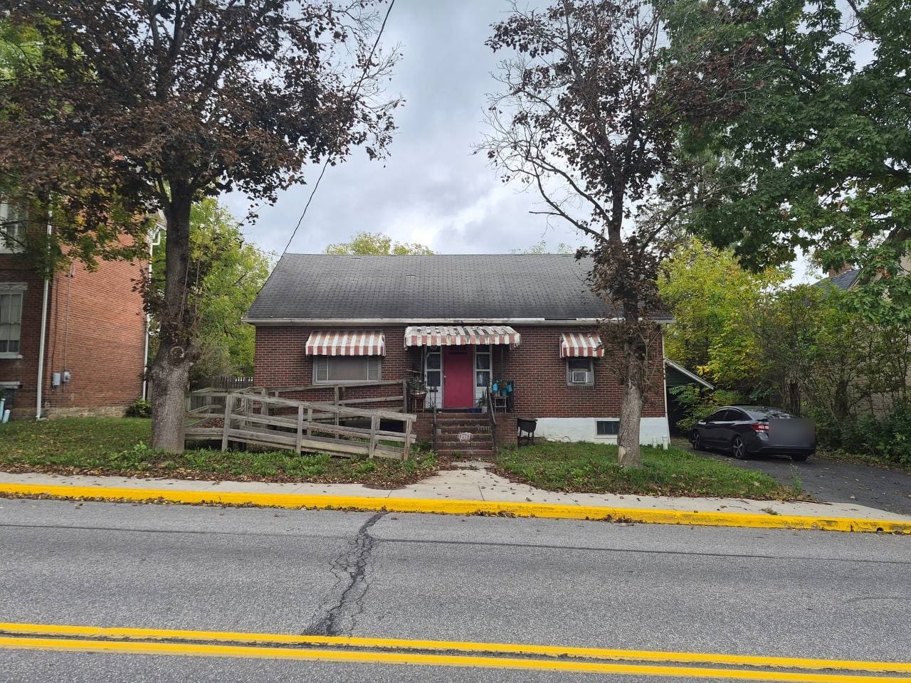 Brick Cape Cod with red front door and wooden ramp at 434 West Pitt Street, Bedford