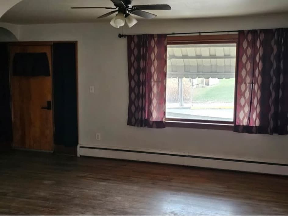 Front-house living room with hardwood floors, ceiling fan and a picture window